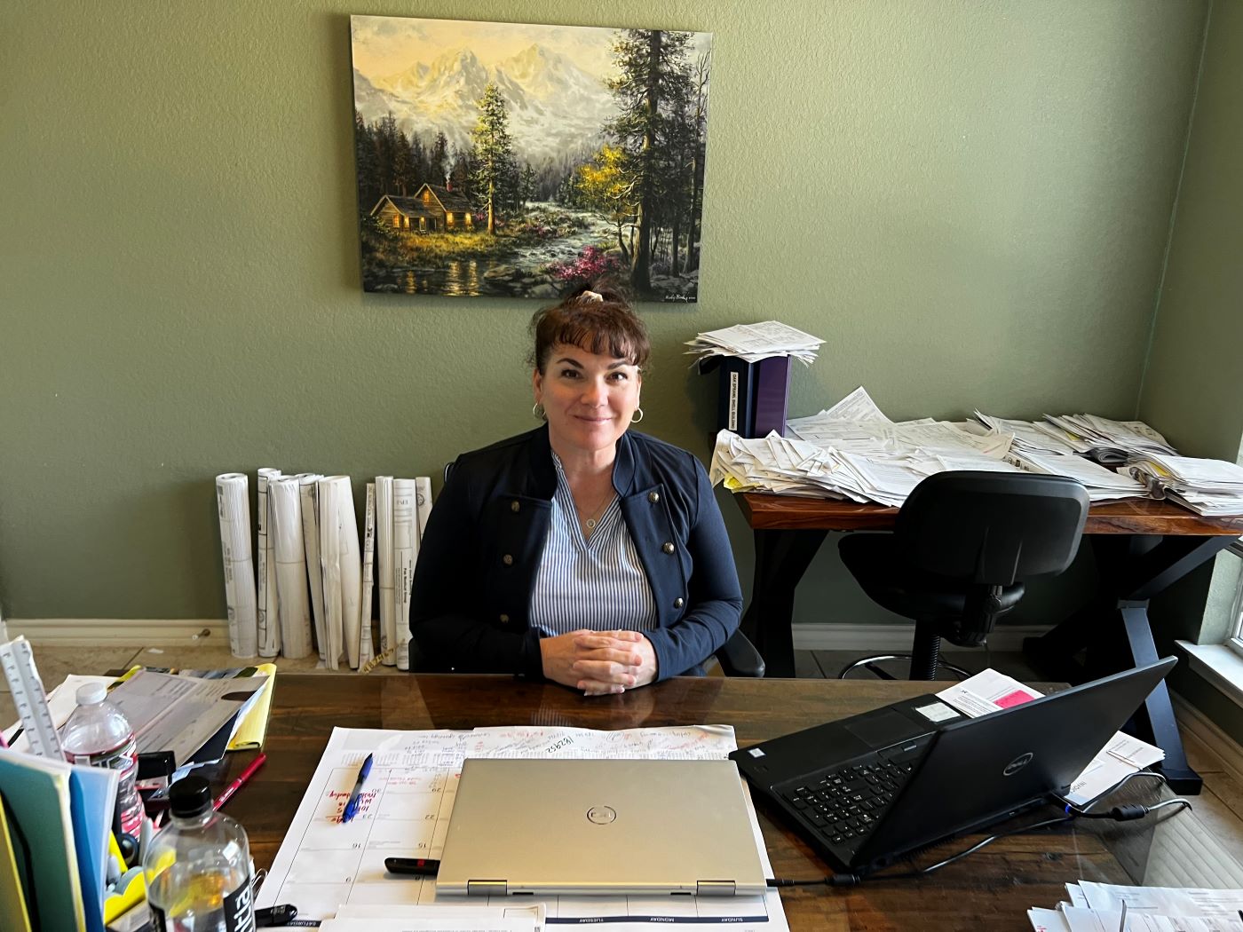 Misty Baker sitting at her 'legendary' home office desk littered with the clutter you'd find at most genius' desks.